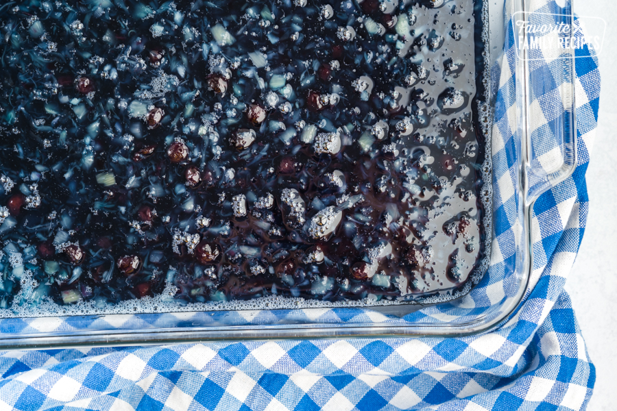 Blueberry Jello mixed with blueberry pie filling and crushed pineapple in a glass baking dish