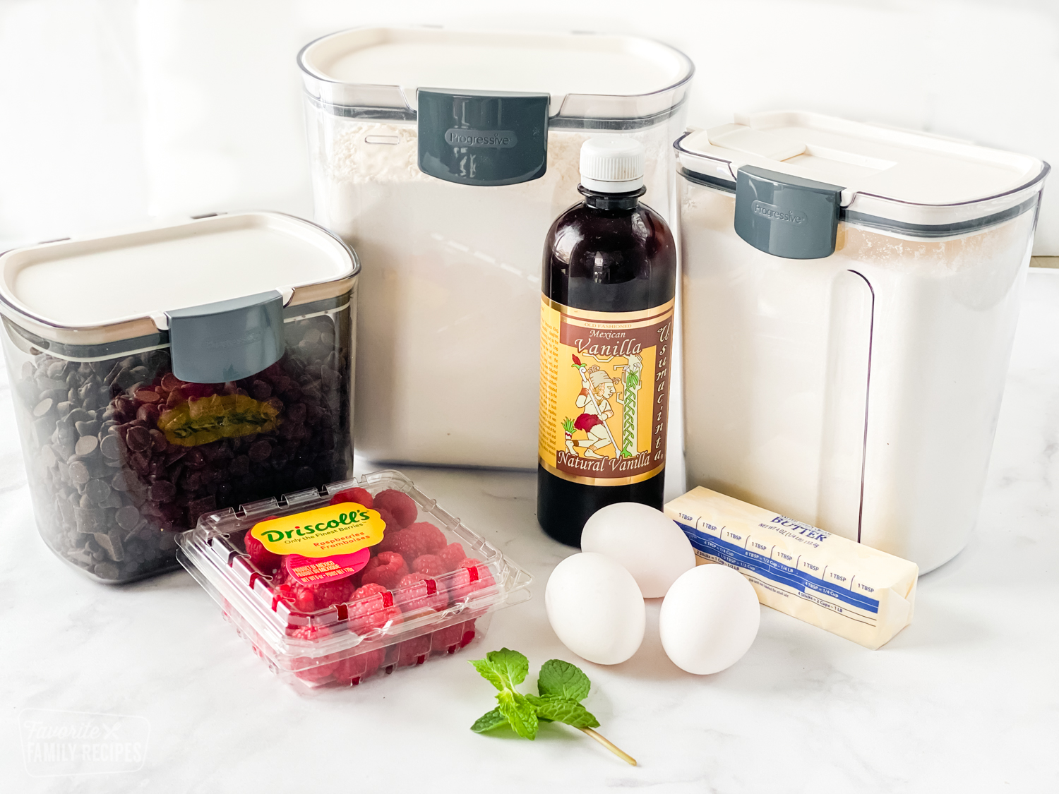 Ingredients to make chocolate lava cake in the instant pot, including flour, sugar, butter, chocolate chips, eggs, vanilla, and raspberries.