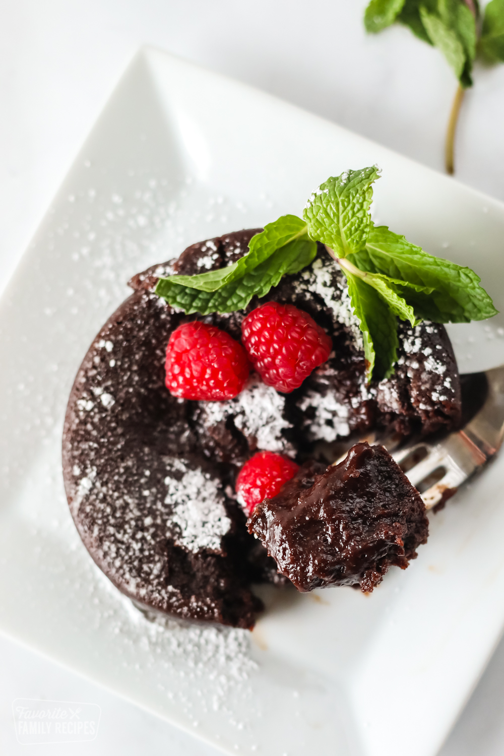 Lava cake on a plate with raspberries and mint garnish