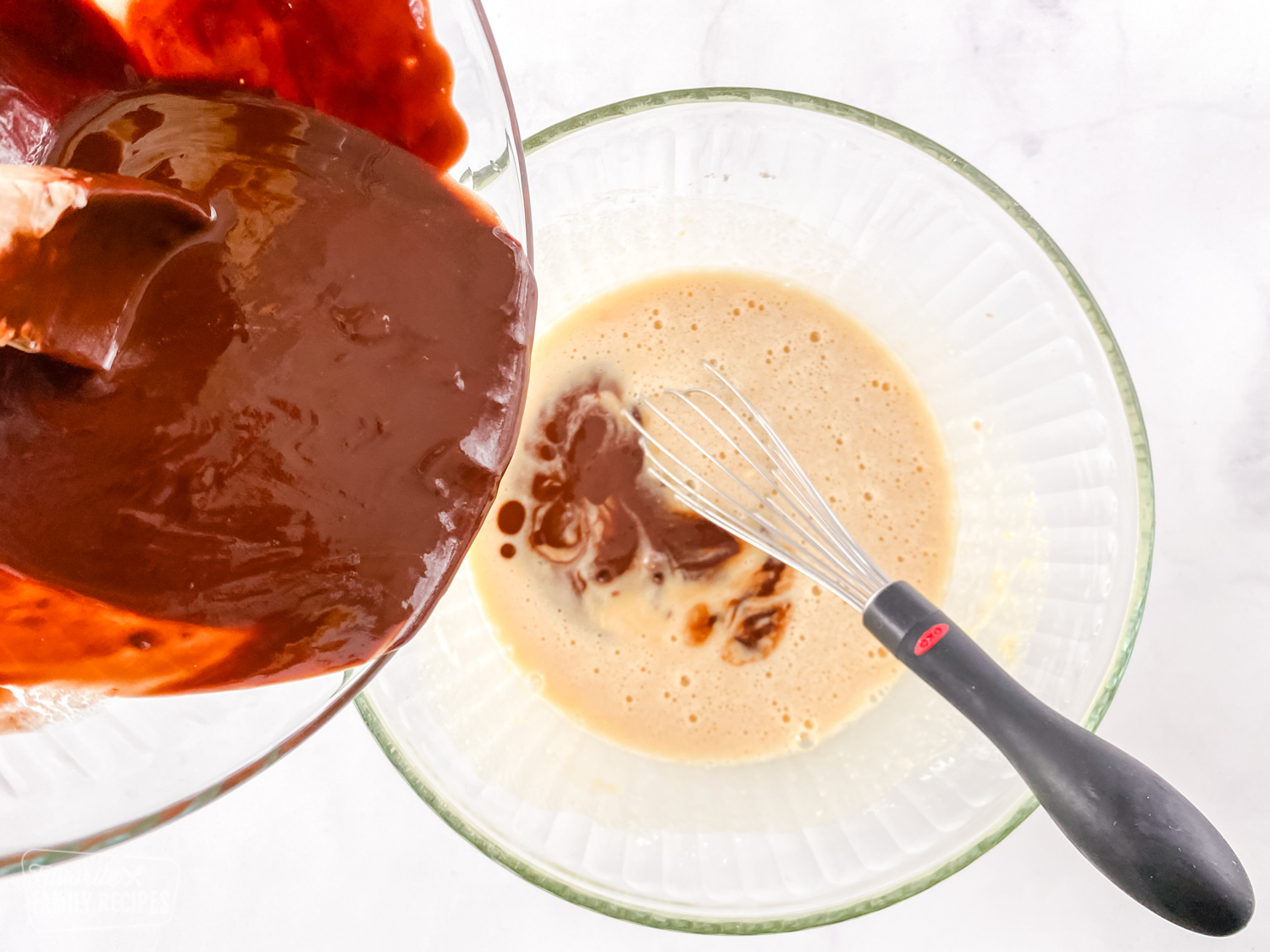 Melted chocolate being poured into a mixture of sugar and eggs to make chocolate lava cake
