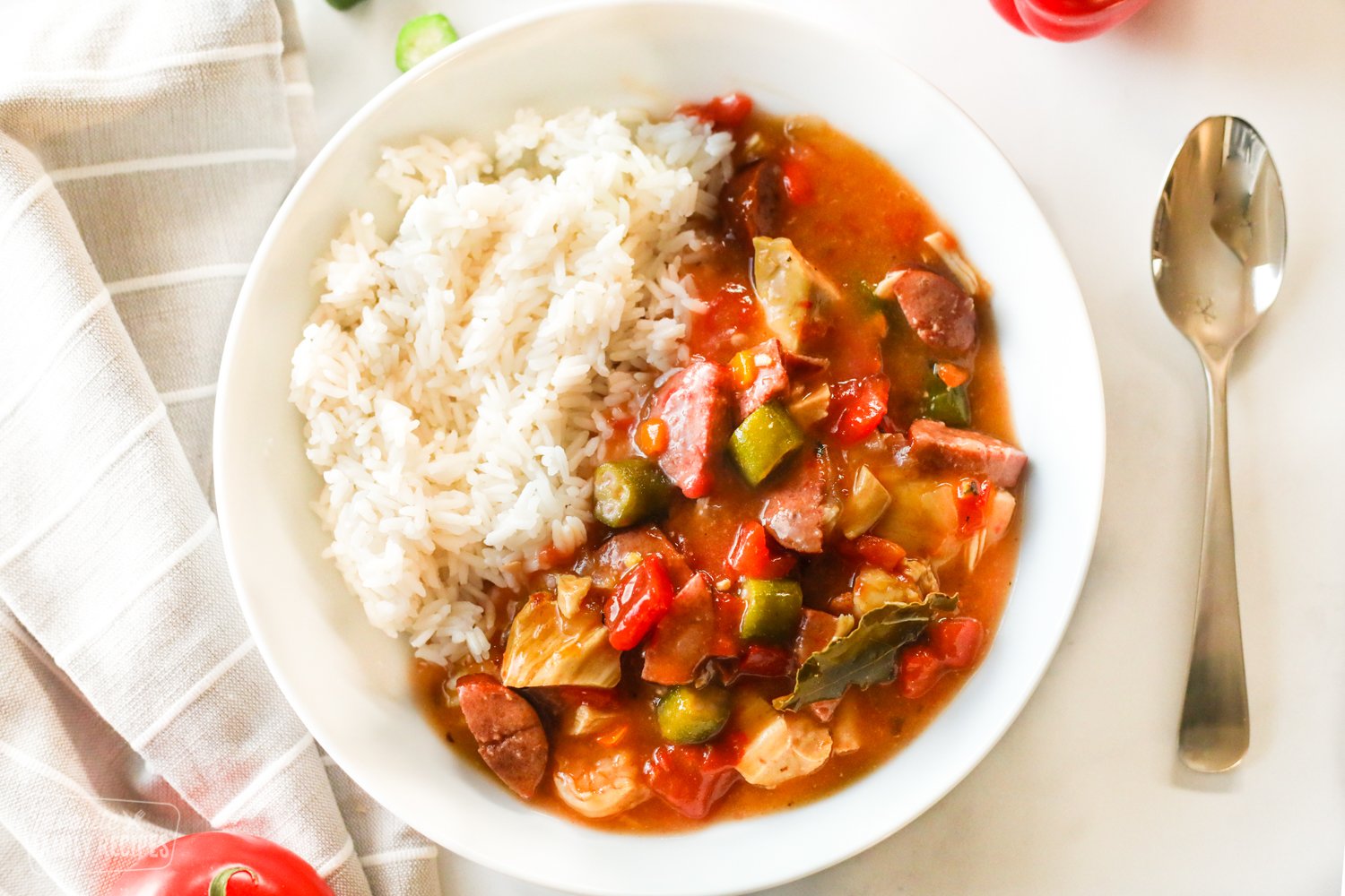 A bowl of Instant Pot Gumbo with chicken, sausage, shrimp, peppers, onion, and okra with rice on the side