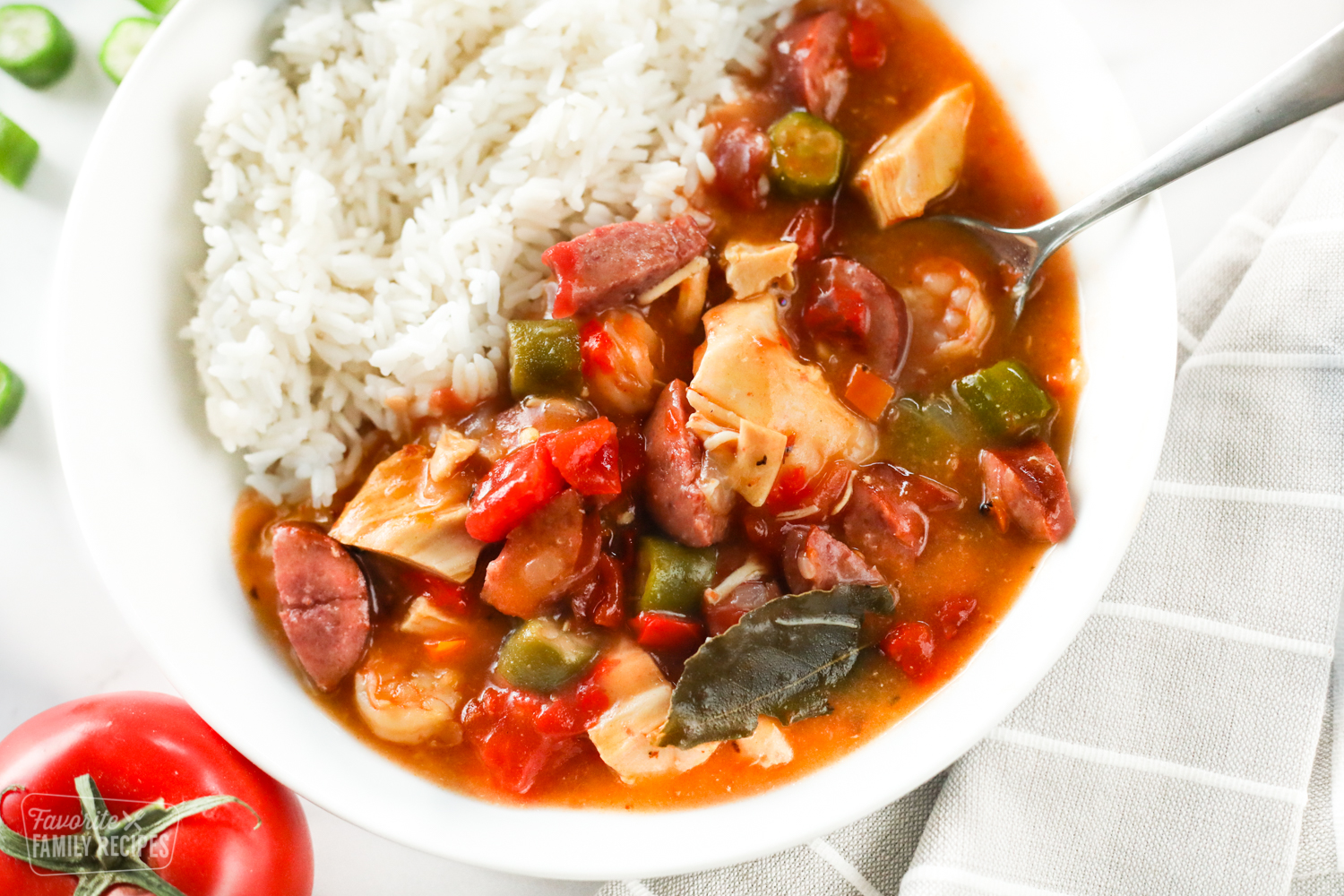 A bowl of Instant Pot gumbo made with chicken, sausage, shrimp, peppers, onions, okra, and seasonings with rice served on the side.