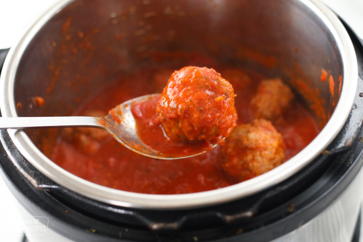 Close up of an Instant Pot Meatball in a serving spoon to show detail of beef and sauce