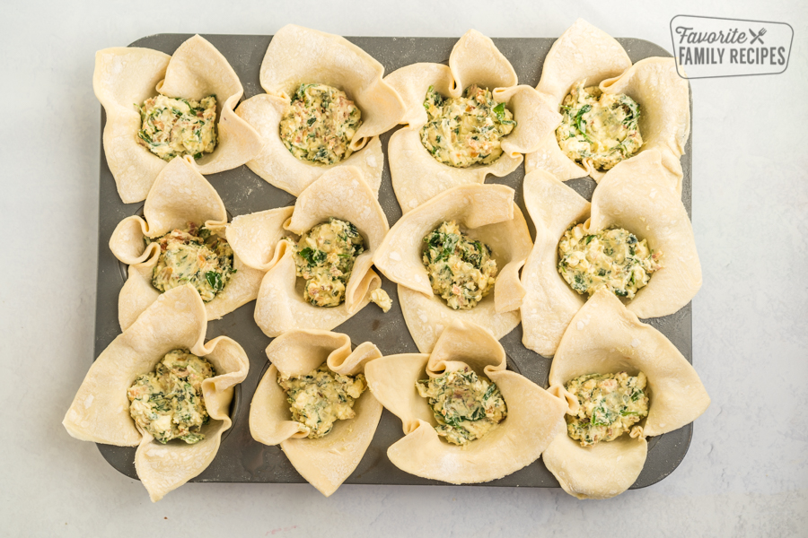 Puff pastry lined muffin tins filled with spinach mixture