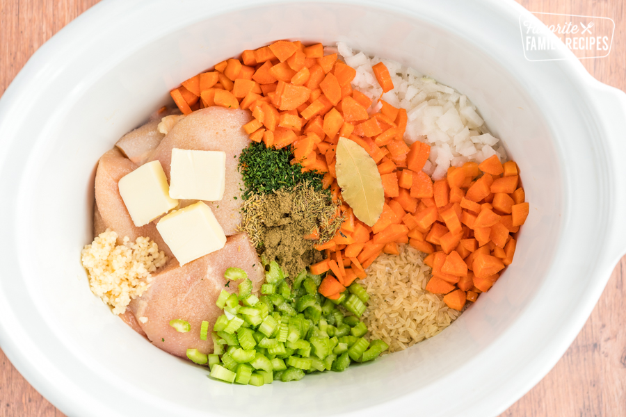 Chicken, carrots, onions, rice, butter, garlic, celery, and spices in a slow cooker.