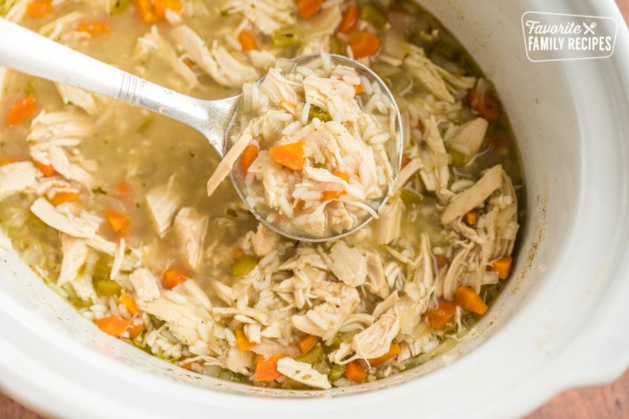 A ladle full of slow cooker chicken and rice soup