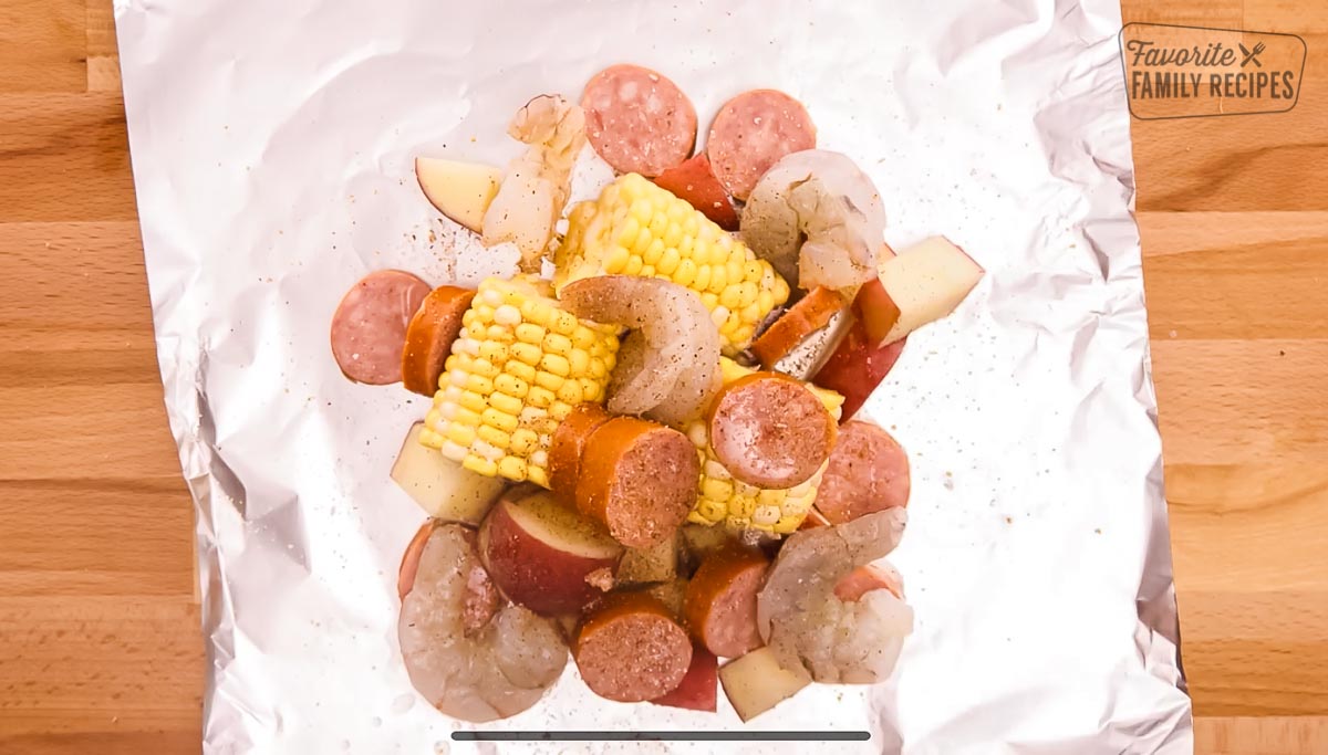 A piece of tin foil topped with shrimp, potatoes, corn, and sausage
