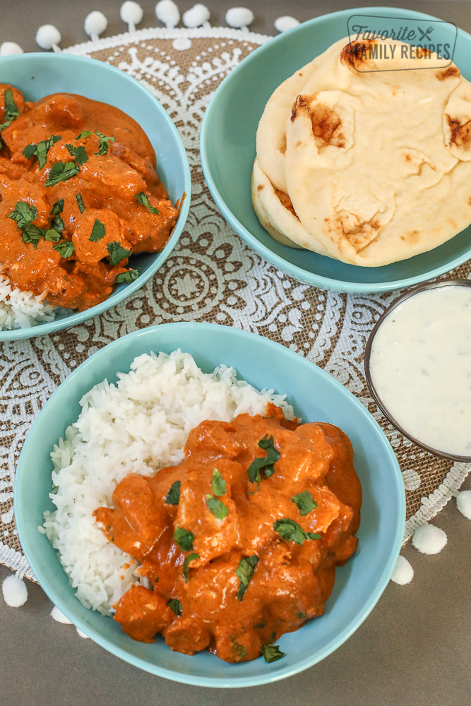 Chicken Tikka Masala in a bowl with rice and a side of yogurt dip and naan bread