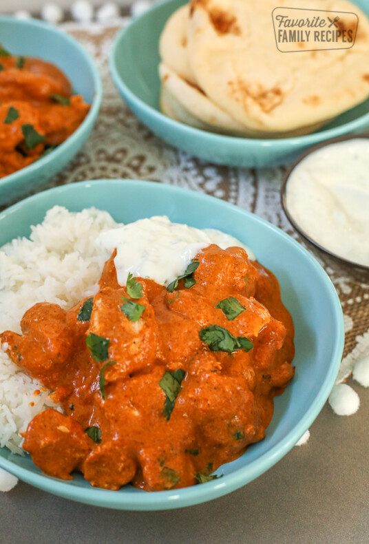 Chicken Tikka Masala in a bowl with rice and cucumber yogurt dip