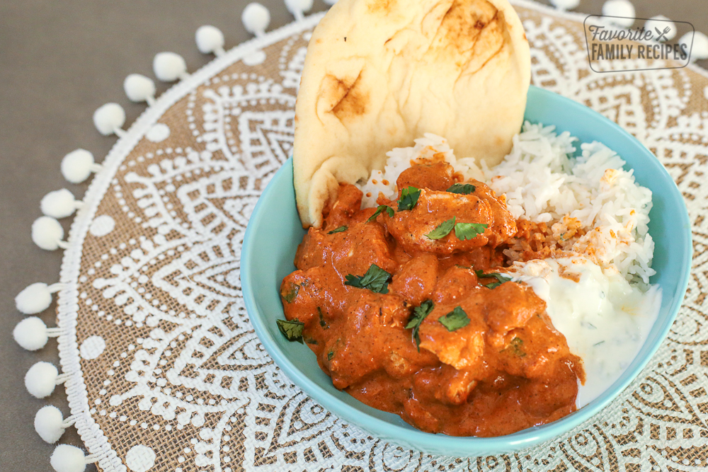 Chicken Tikka Masala in a blue bowl with rice, yogurt, and naan bread.