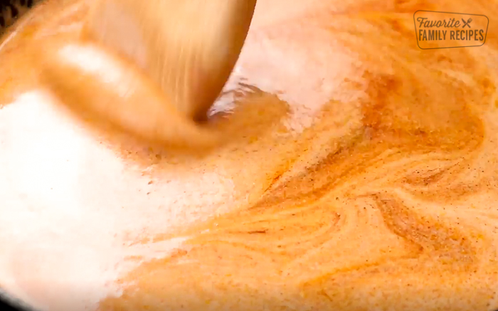 Cream being stirred into spices