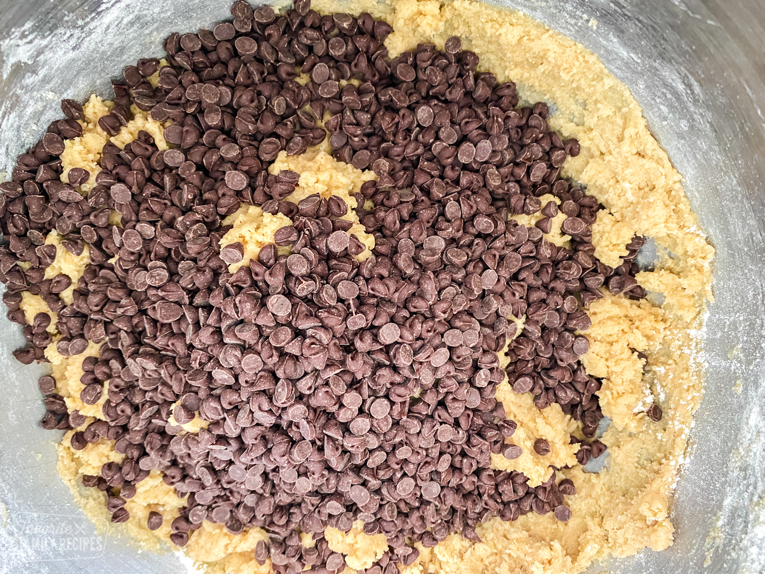 Mixing bowl with chocolate chip cookie dough with chocolate chips over the top