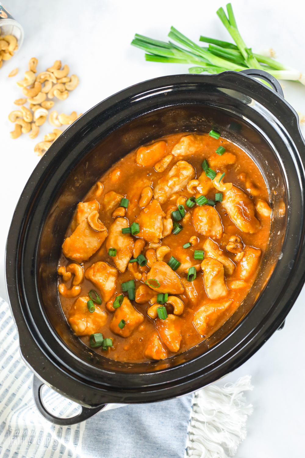 Crock Pot Cashew Chicken in sauce in a Crock Pot with cashews, chicken, and green onion