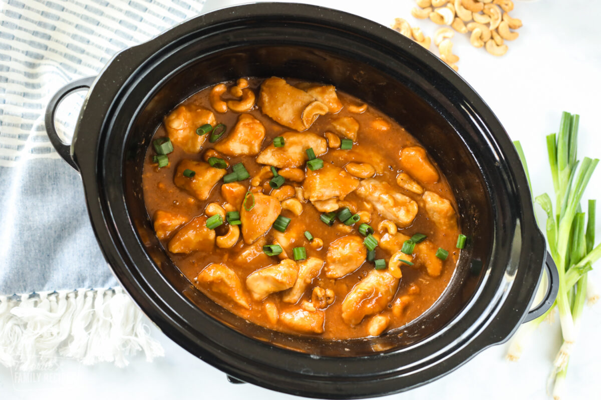 Crock pot Cashew chicken in a slow cooker with cashews and green onion.