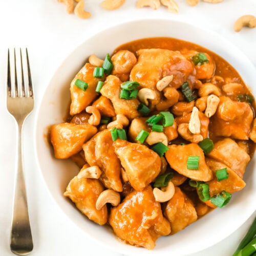 Cashew Chicken in a bowl next to cashews and green onion