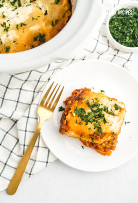 A slice of crock pot lasagna on a white plate with a gold fork