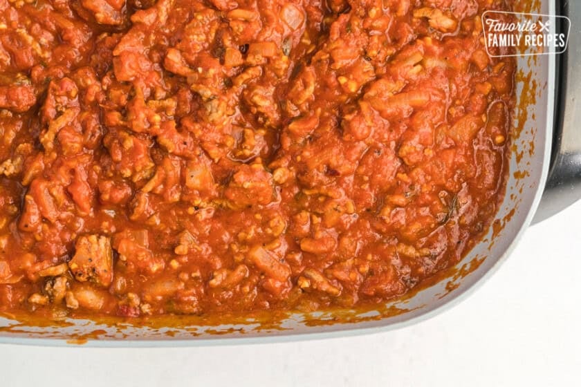 Tomato sauce, ground beef, and onions cooked in a skillet