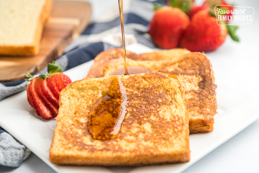 Maple syrup being poured onto a plate of french toast slices