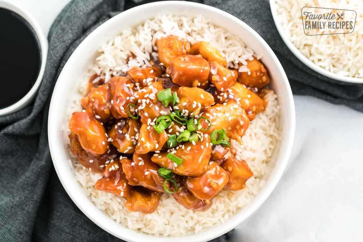 General Tso's chicken over top of rice and in a white bowl. 