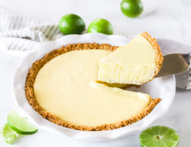 A plain slice of key lime pie being lifted from a pie pan with a pie knife