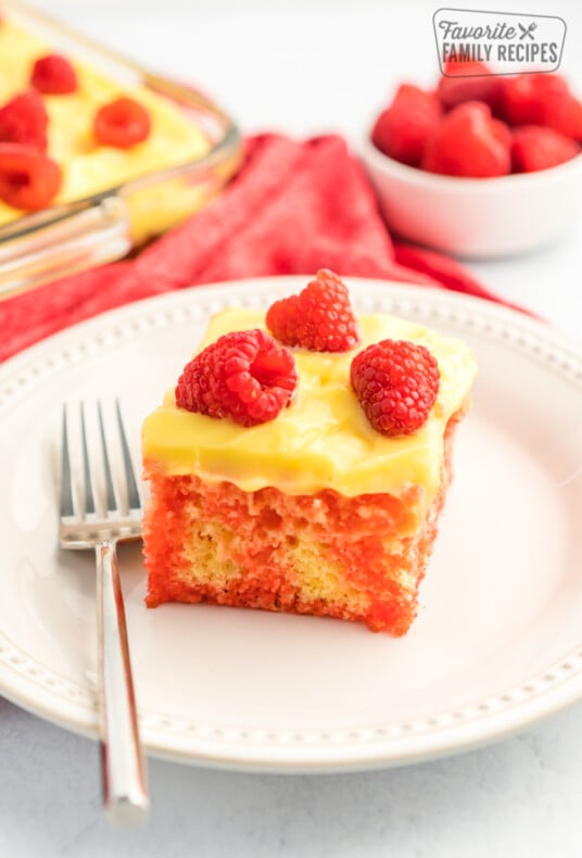 Raspberry Lemon Jello Poke Cake topped with lemon pudding frosting and fresh raspberries