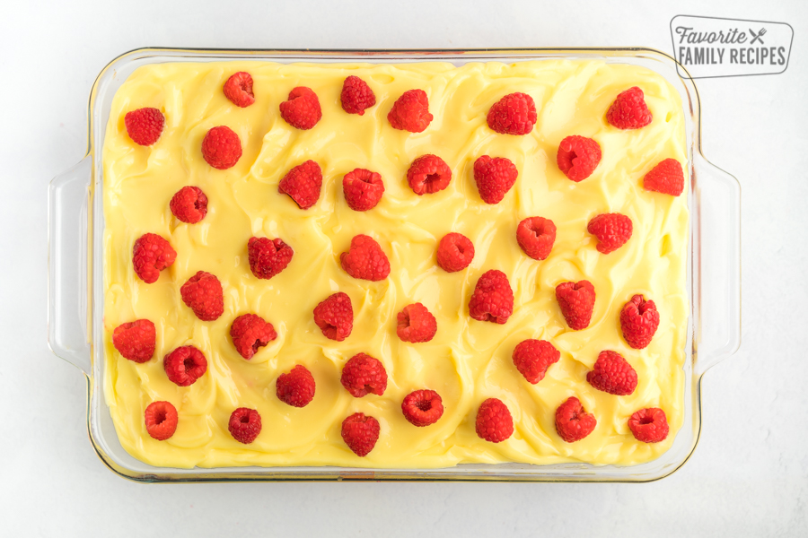 A cake with lemon frosting and raspberries
