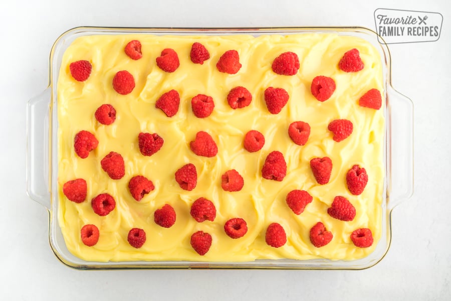 A cake with lemon frosting and raspberries.