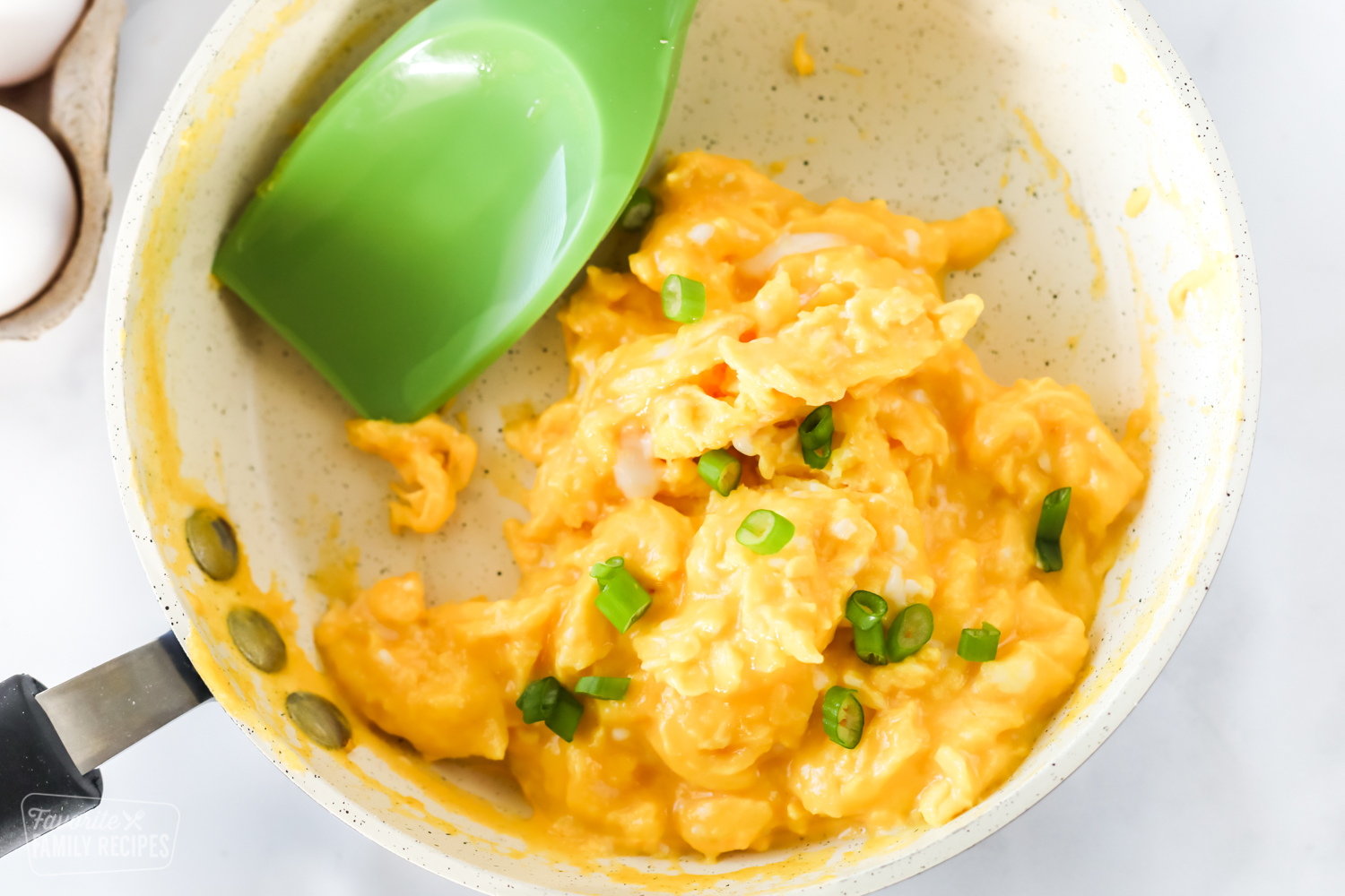 A top view of scrambled eggs in a pan sitting on a counter.