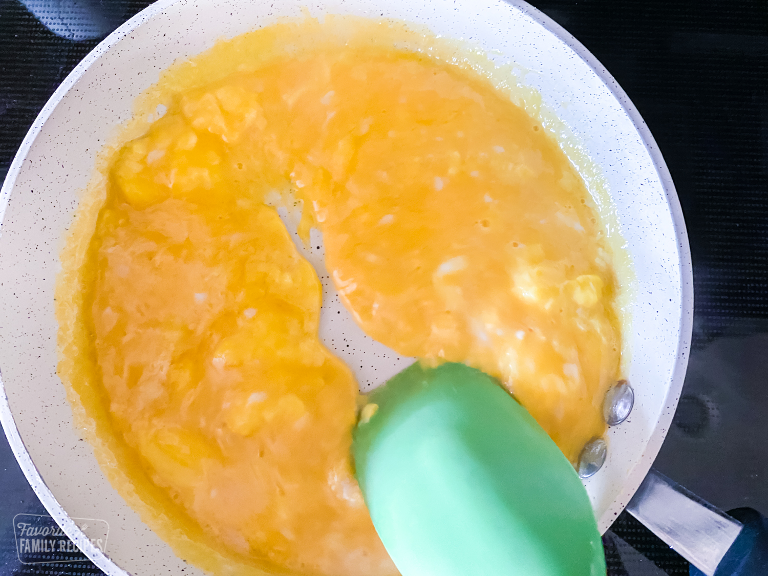 Eggs being heated in a pan and turning into curds for scrambled eggs.