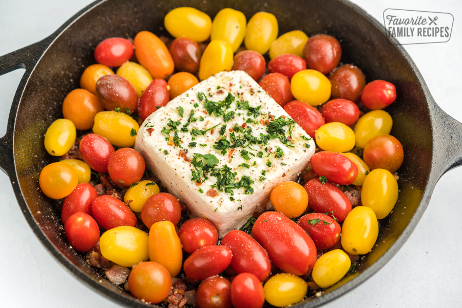 Heirloom cherry tomatoes and a block of feta cheese in a cast iron skillet