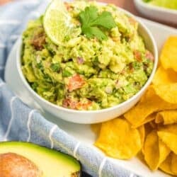 Guacamole in a small bowl topped with a lime slice and a cilantro leaf