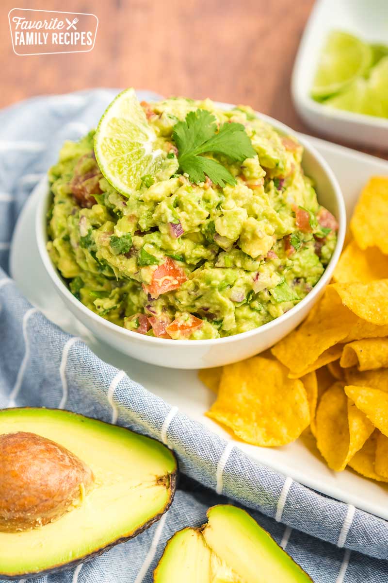 Guacamole in a small bowl topped with a lime slice and a cilantro leaf