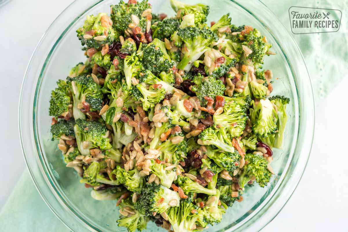 Chopped broccoli salad with bacon and craisins in a clear bowl