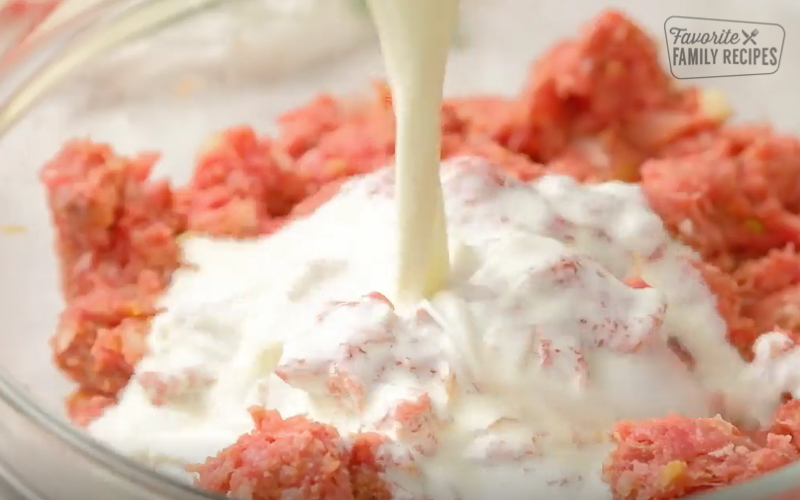 Pouring cream into meatball mixture.