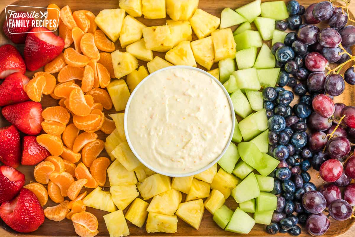 A tray full of fruit with a bowl of fruit dip
