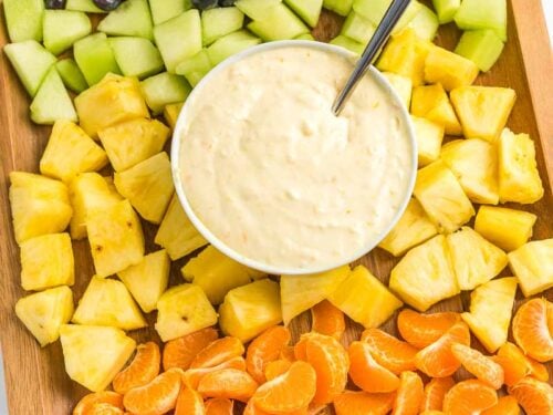 A bowl of fruit dip surrounded by fruit