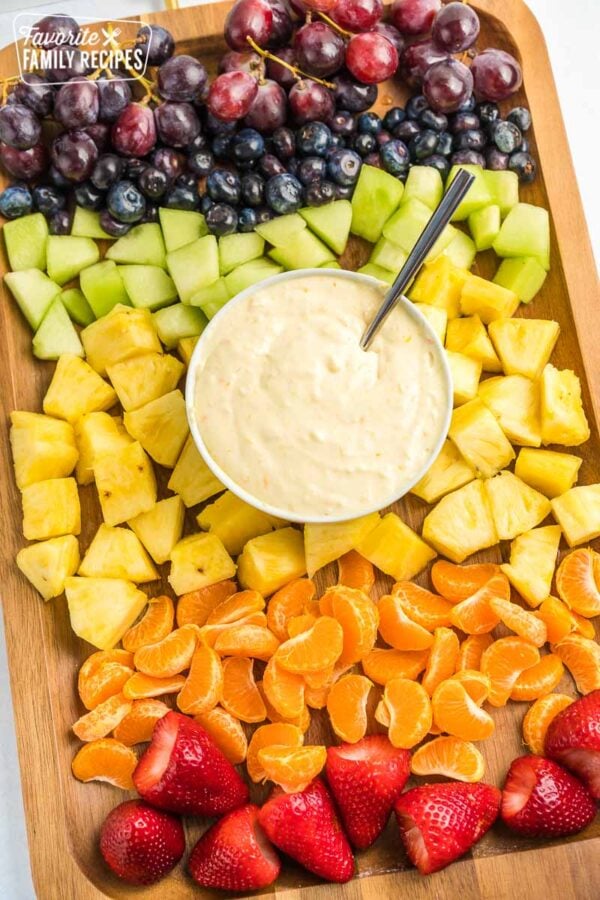 A bowl of fruit dip surrounded by fruit