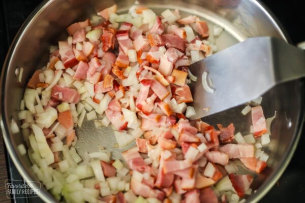 Bacon and onion being sautéed together in a pan.