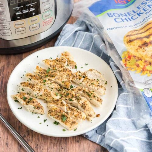 Sliced chicken on a plate with an instant pot and a bag of frozen chicken in the background