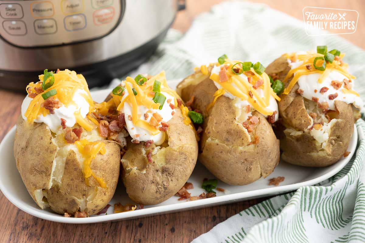 Four baked potatoes, cut in half and loaded with sour cream, cheese, bacon, and green onions.