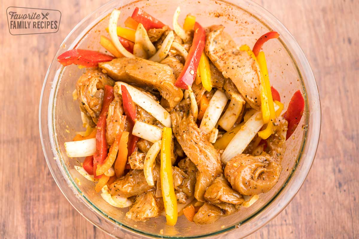 Chicken, pepper, and onion slices in a large bowl