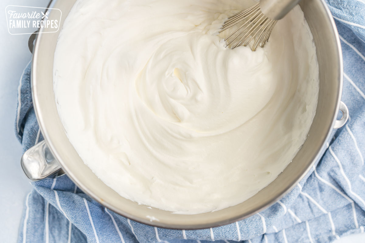 A metal mixing bowl filled with whipped cream