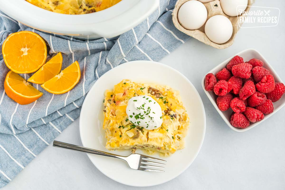 A piece of breakfast casserole on a plate topped with sour cream.