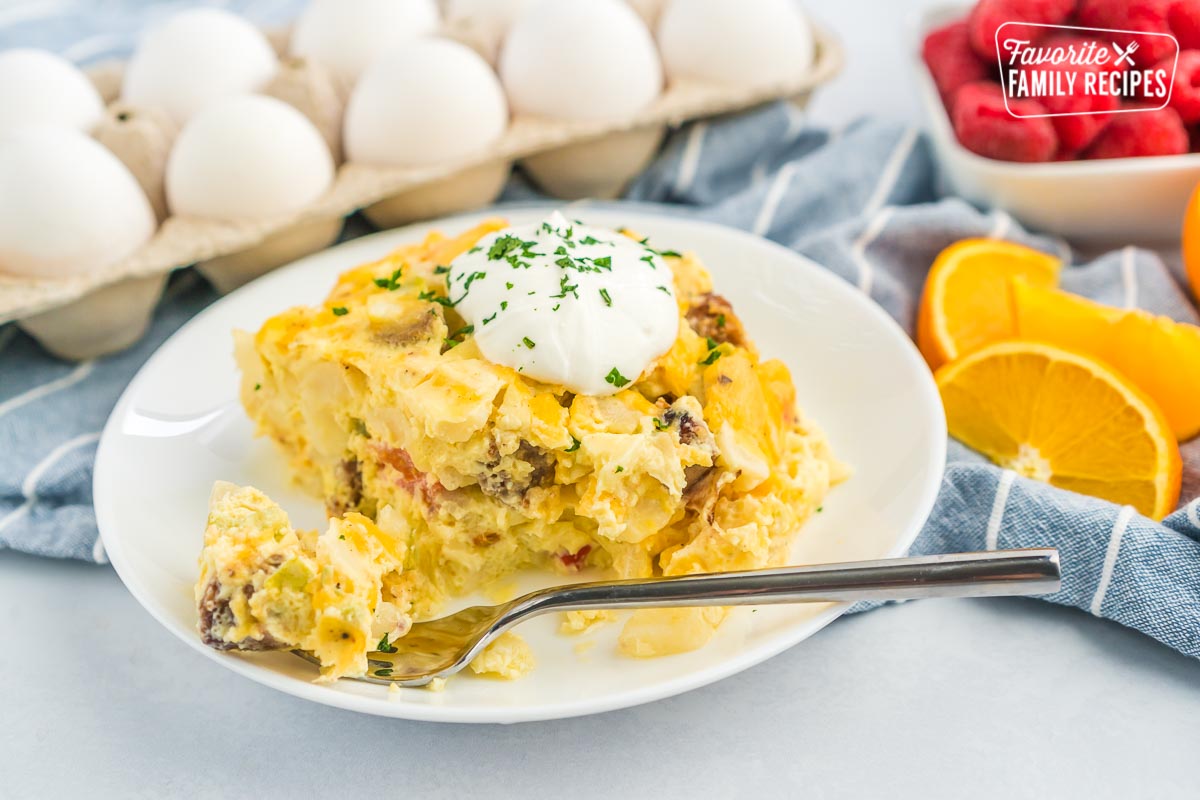 A slice of breakfast casserole with a bite taken out of it with a fork.