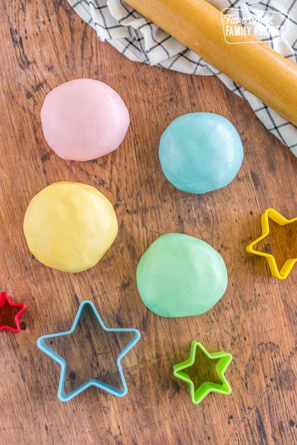 Four fondant balls in pink, blue, yellow, and green with star cookie cutters on the side