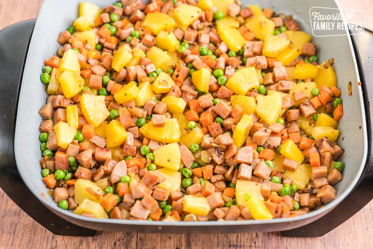 Ham, pineapple, peas, carrots, onions, and garlic in a pan