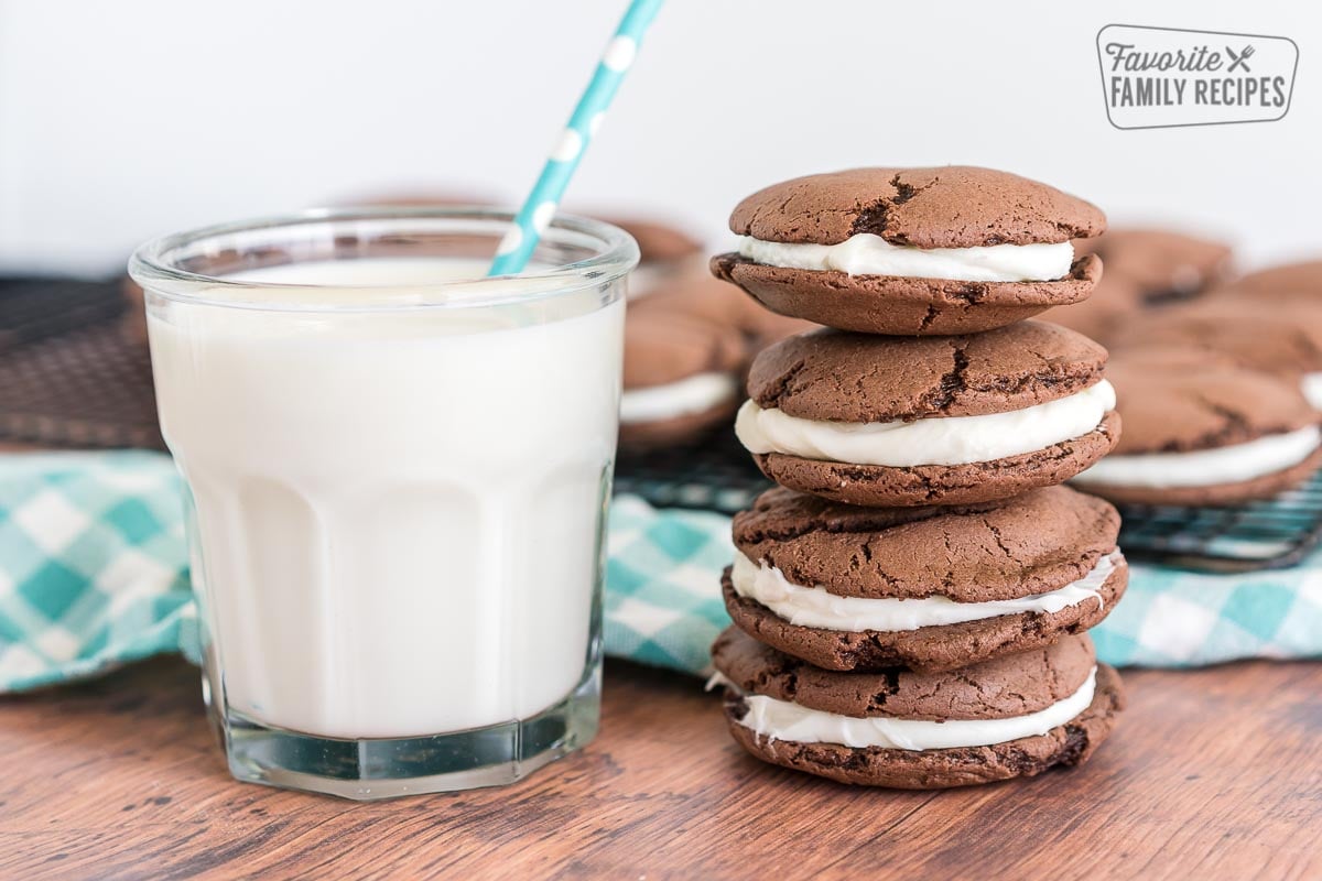 A stack of homemade oreos with a glass of milk.