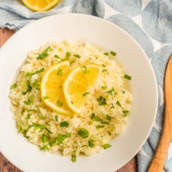 Lemon rice in a white bowl topped with lemon slices