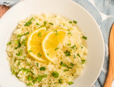 Lemon rice in a white bowl topped with lemon slices