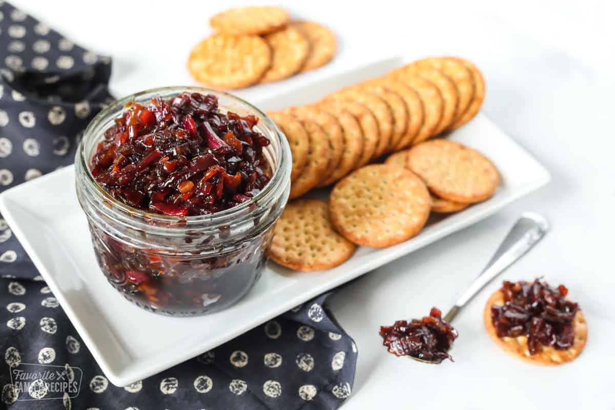 Bacon jam in a jar next to a plate of crackers